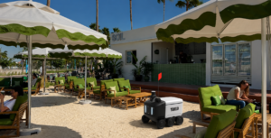 Autonomous delivery robot serving drinks at a Dubai robot cafe on Kite Beach.